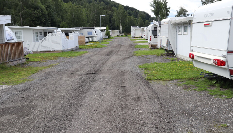 Ett av de nye kravene er at brannvesenet skal kunne komme seg fram mellom ulike teiger med sesongplasser der det campes. Bildet er av bred grusvei mellom to rader campingvogner på faste plasser med spikertelt.